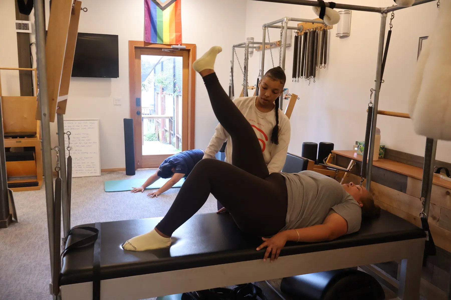 Teacher guiding a student through leg work on a Cadillac