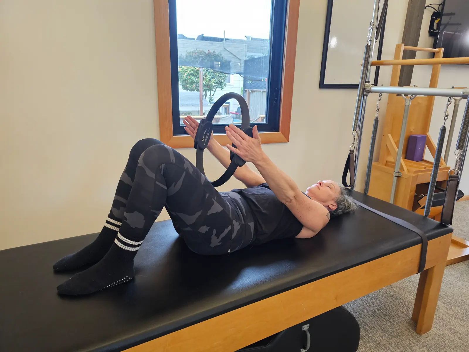 Student practicing with a Pilates ring on studio equipment