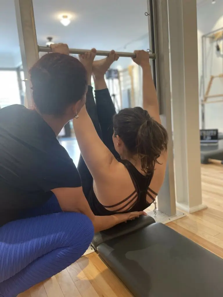 Teacher Trainer guiding a student through Classical Pilates equipment work